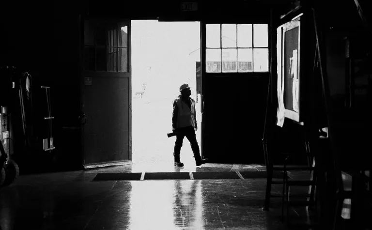 A silhouette of a person with a camera in a large doorway