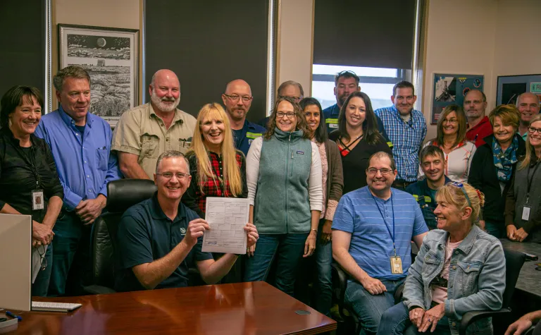 Surrounded by Sanford Lab staff and partners, Mike Headley, executive director of Sanford Lab, signs the Cooperative Agreement