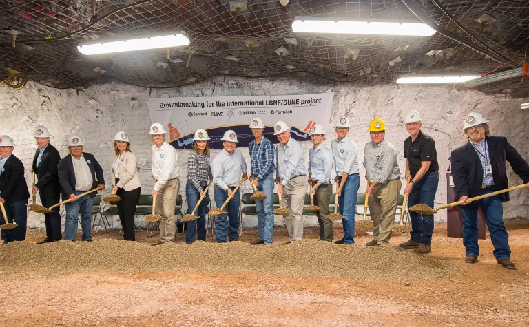 14 people with shovels break ground on a new experiment.
