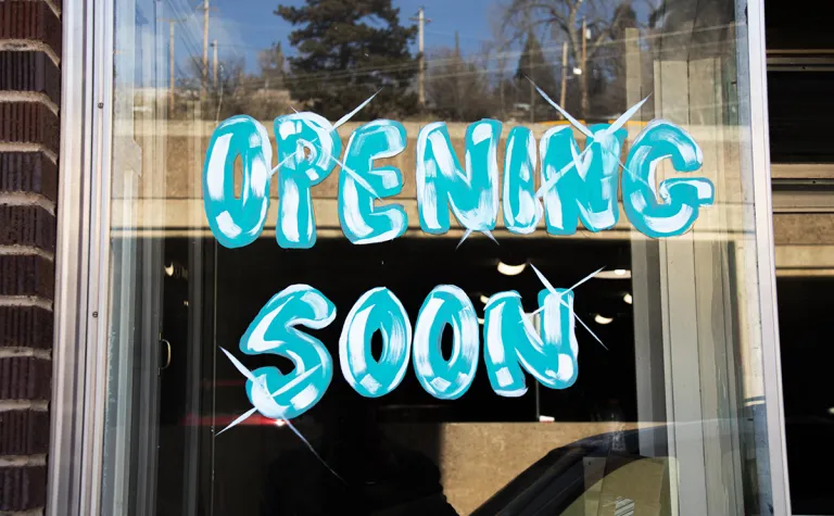 The words "Opening Soon" are written in window pain in a storefront