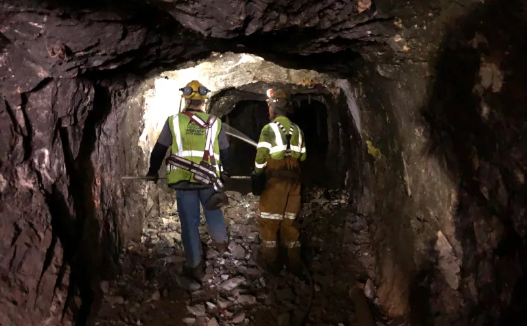 Two workers walk down an illuminated underground tunnel