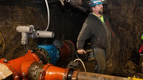 man stands next to underground water pipe