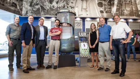 group of people standing in front of lux detector exhibit in the visitor center