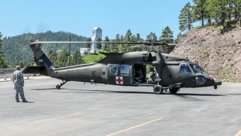 army blackhawk helicopter idles in a parking lot. 