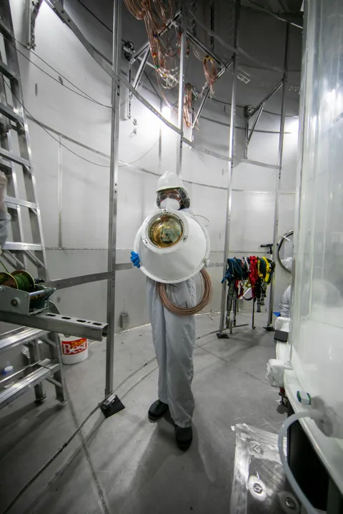 A woman holds a photomultipler tube ready to install.