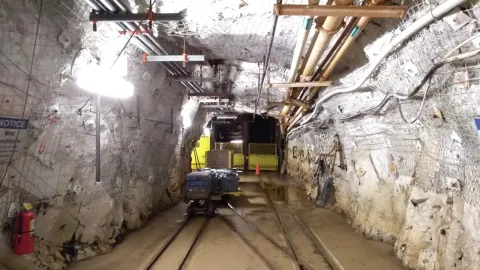 a drift near the landing of the 4850L with mine carts and rails and a cement floor 