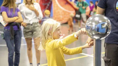 A child plays with a hands on science experiment during Neutrino Day 