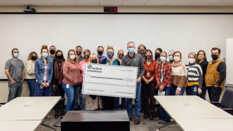 group of people holding a giant check