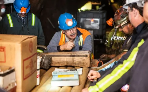 engineers and technicians  in hard hats talking over boxes of geologic core samples 