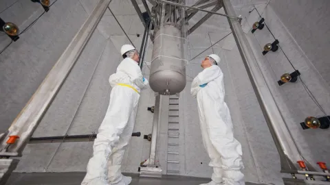 two researchers peer up at the LUX detector at SURF