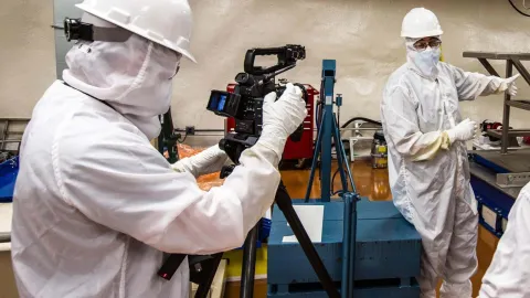 person filming scientist in cleanroom