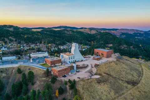 a shot from the sky of the Yates headframe and the SURF admin building and other structures in the sunrise on a fall morning. 