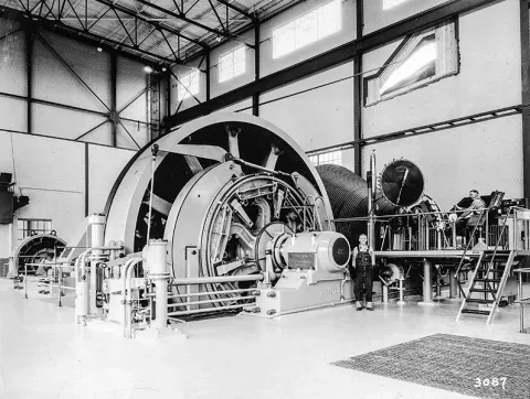 "The Nordberg Manufacturer’s double drum hoist is shown from above. The diameter at one end is 25 feet and tapers to a diameter of 12 feet at the other end, allowing them to sit opposite each other and shrink the footprint of the drums. Courtesy Siemag Tecberg, Inc." image "black and white photo of…ists aligned from above"