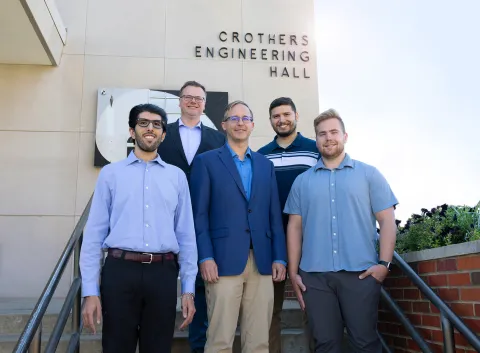 The team at SDSU working on DUNE argon modeling are posed on a set of steps outside on campus, includes Vishnu Pfeiffer (M.S. student), Dr. Stephen Gent (Professor), Dr. Gregory Michna (Associate Professor), Sahil Sharma (M.S. student), and Hunter Wallster (M.S. student). 