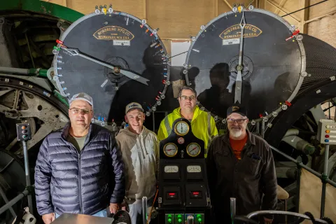 Four hoist operators at SURF in front of dials used in a hoisting mechinism.