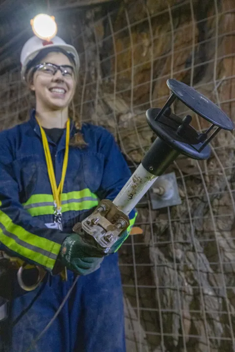 A student holds one of the modified underground weather stations that monitors air flow at SURF.
