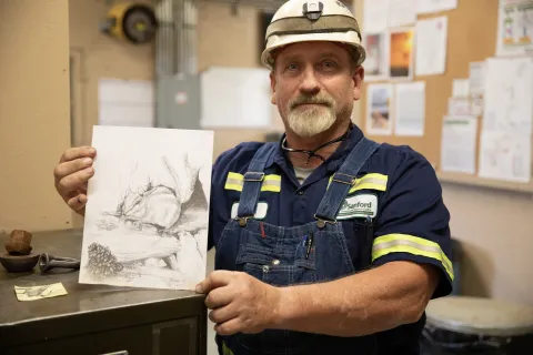 Dan James holding a piece of his artwork a pencil drawing of a chipmunk.