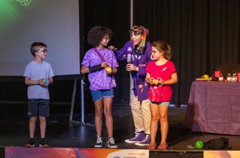 Professor Sko on stage with 3 children