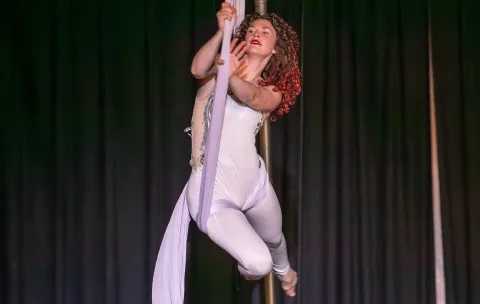 An aerialist swings on silks