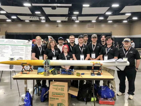 Group photo of UND students with a rocket
