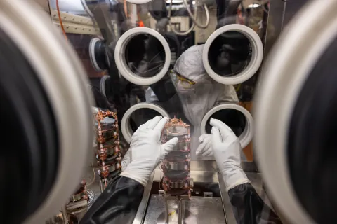 A researcher works inside a glove box on experiment components. 