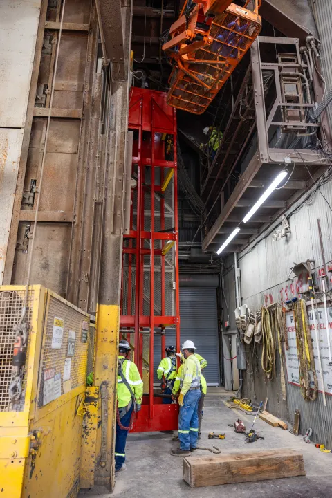 A crew of engineers and technicians at SURF installing the new shaft conveyance, or "cage" with a floor measuring 4.5 by 5 feet square and sides 60 feet high. This cage will be used to transfer long steel beams from the surface to 4850 feet below ground for use in constructing the Deep Underground Neutrino Experiment.