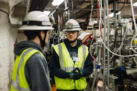 Two students stand inside the CASPAR experiment 