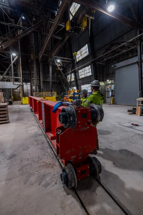 Technicians prep one fo the DUNE cryostat beams for loading into the cage