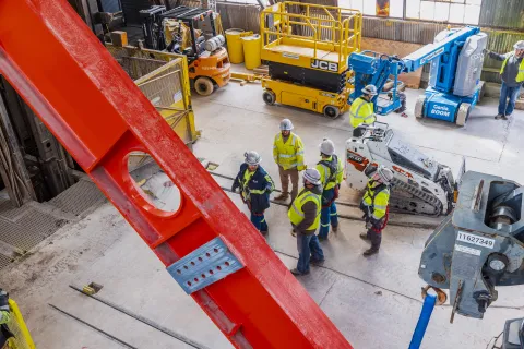 Technicians rig DUNE cryostat beams for loading into the cage - middle of loading. 