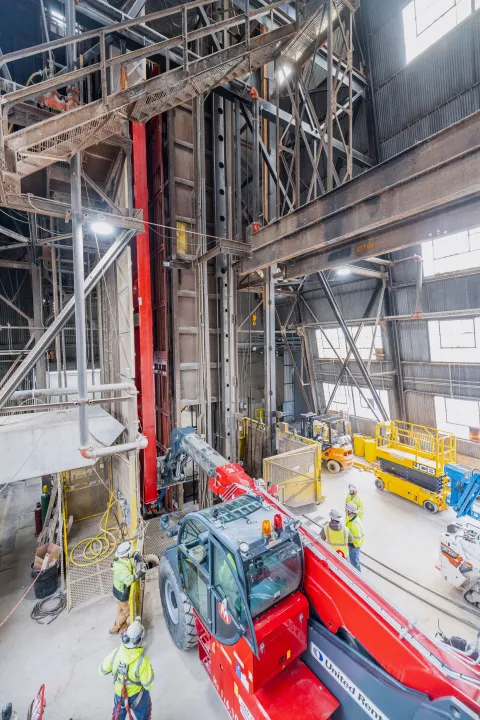 Technicians rig DUNE cryostat beams for loading into the cage - the beam is in the cage. 