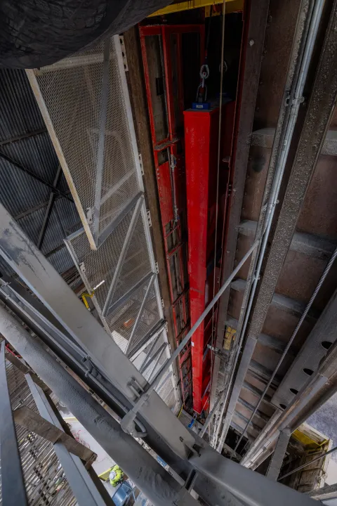 Technicians rig DUNE cryostat beams for loading into the cage - secured in the cage. 