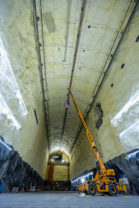 A crane on the floor of the DUNE Cavern holding an American Flag.