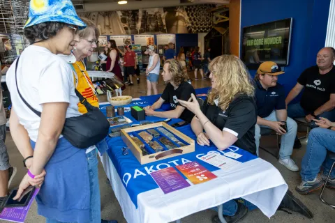 Two women talk to two scientists at a Neutrino Day booth 