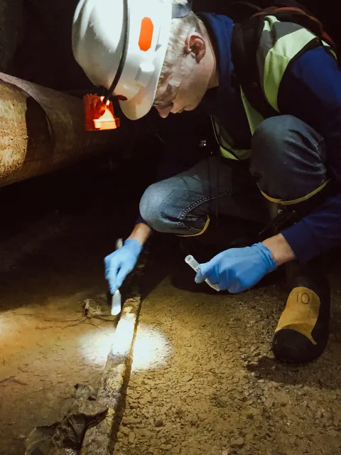 a person collects a sample in a dark tunnel