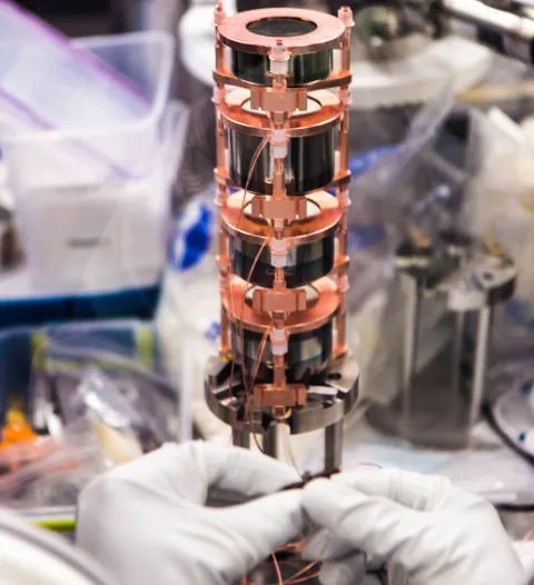 One string of detectors is shown. Parts made of the world’s purest copper hold the detectors together. The experiment’s first batch of detectors was made of natural germanium. Those detectors were uniformly 0.6 kg. Subsequent batches of detectors were enr