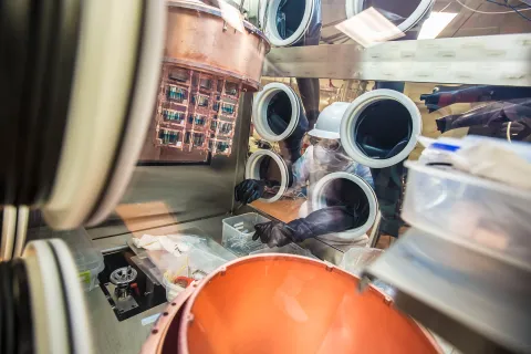 John Wilkerson installs the germanium detector strings into the cryostat. Each string shown here includes four detectors. The strings are configured to fit within the copper cylinder of a cryostat. Of the font style=