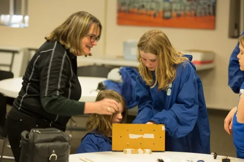 Peggy Norris speaks with two students about an engineering challenge.