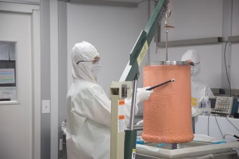 Cabot-Ann Christofferson, a South Dakota Mines chemist with the Majorana Demonstrator, examines a metal cylinder coated with electroformed copper. Photo by Adam Gomez 