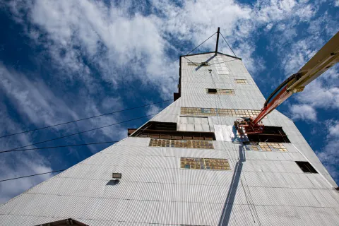 Crews do work on a headframe from an elevated platform