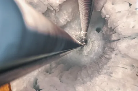 A hole is drilled deep into the ice