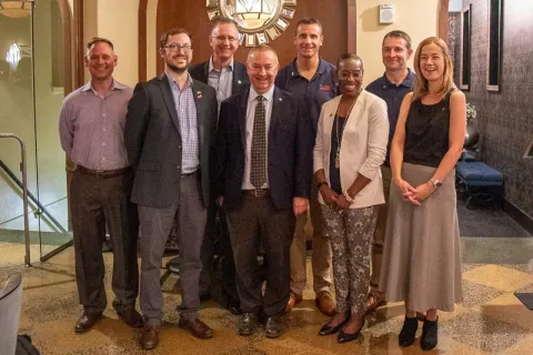 Seven people stand for a group photo. IDs in caption.