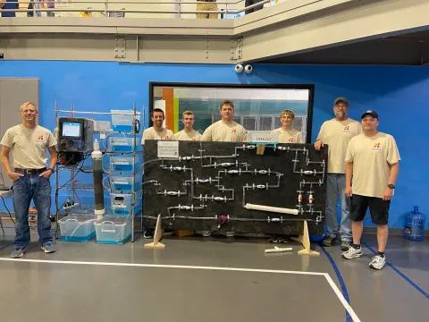 seven men stand behind a water display