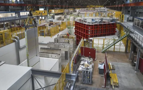The recently arrived anode plane array (hanging on the left) is moved by a crane to its new home in the ProtoDUNE cryostat. Photo: CERN