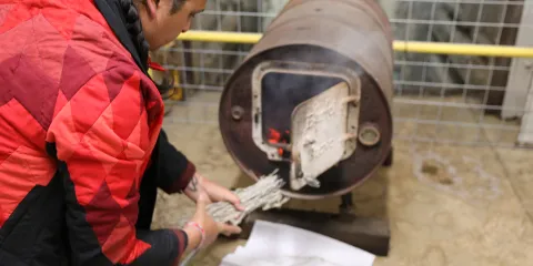 Marty Two Bulls Jr. burns sage at the top of the Ross Shaft inside a small wood stove. 