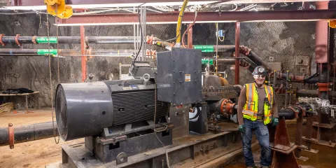 Andrew Brosnahan, a professional engineer at SURF, and one member of the team that updated the 3650 pump room, poses near the new pump.