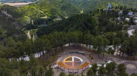 A shot of the Sanford Underground Research Facility (SURF) in the Black Hills showing Čhaŋgléška Wakȟáŋ, the ethnobotanical garden at SURF, and the Ross Headframe.