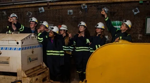 students stand underground pointing into the middle distance