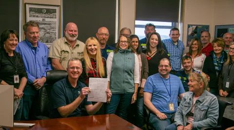 Surrounded by Sanford Lab staff and partners, Mike Headley, executive director of Sanford Lab, signs the Cooperative Agreement