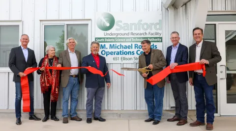 people hold a ribbon that has just been cut