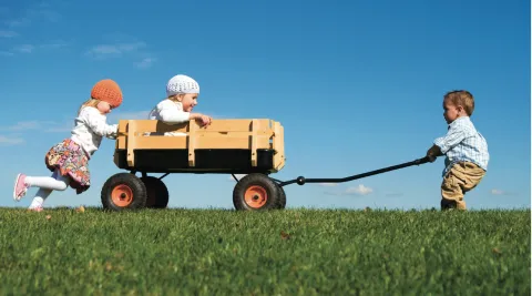 Kids pushing and pulling on a wagon.